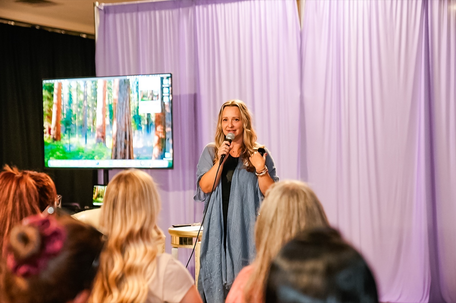 A guest speaker against lavender drapes