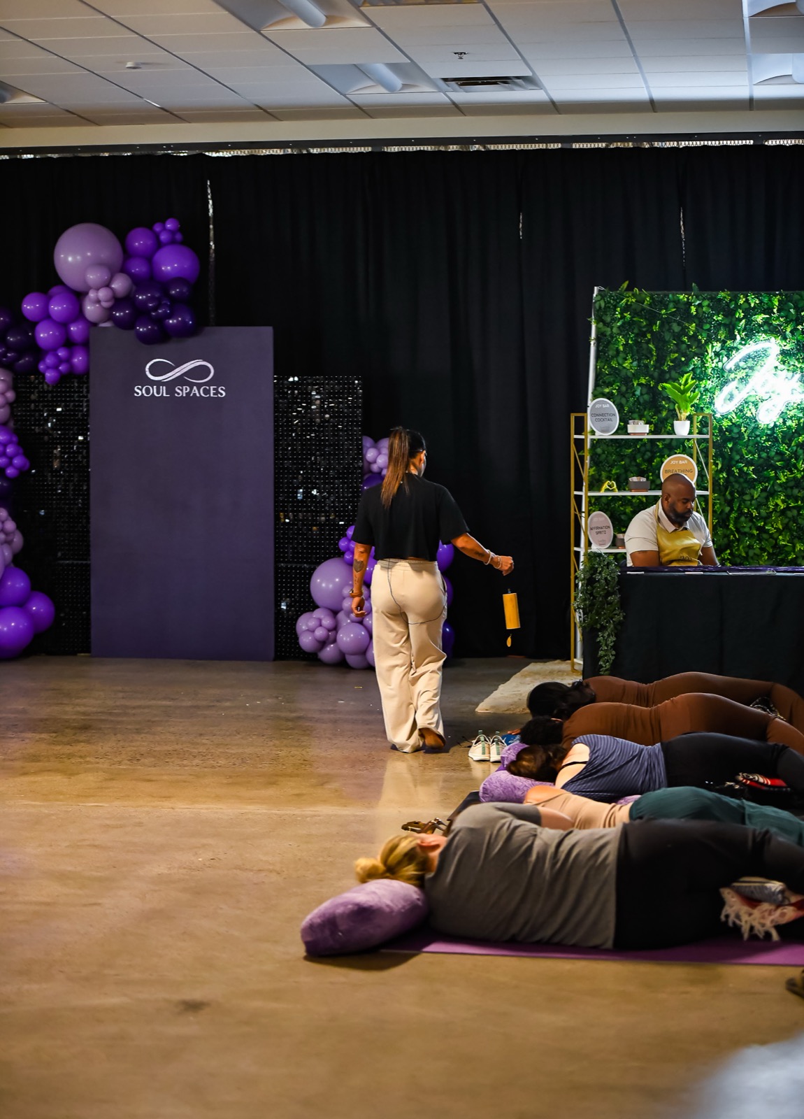 Erlinda crosses the space: backdrop, balloons, Joy Bar, and mats in one frame