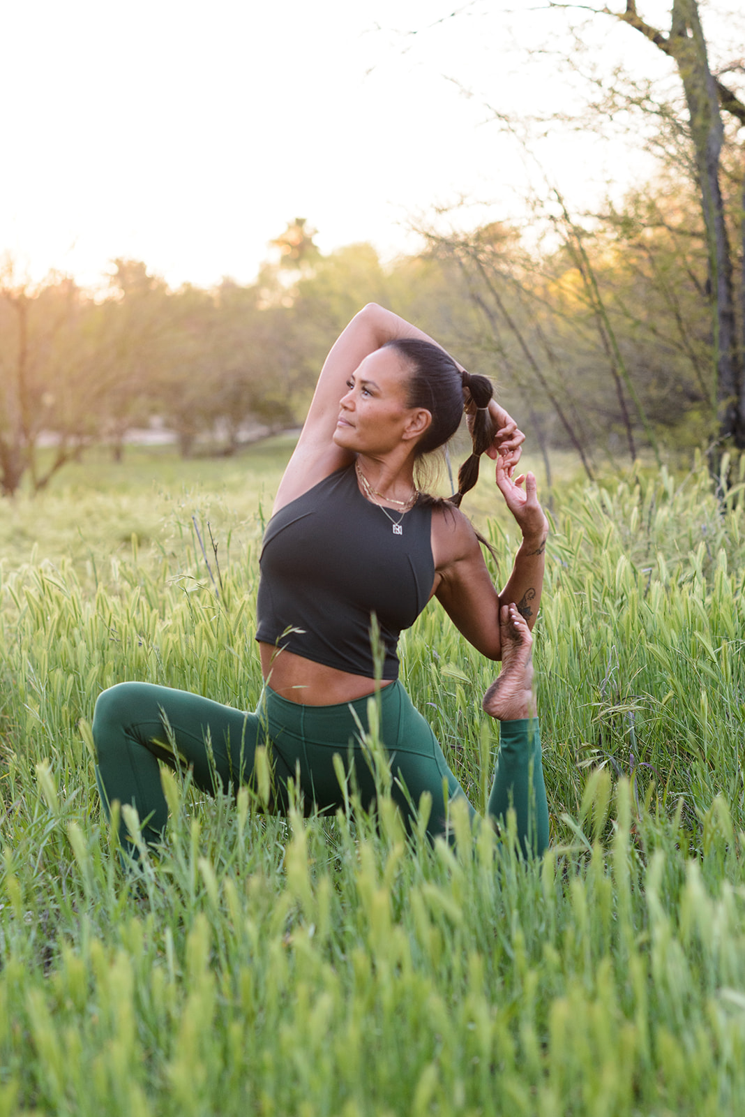 Jenny Guzon-Bae in a yoga pose in a grassy field at sunset